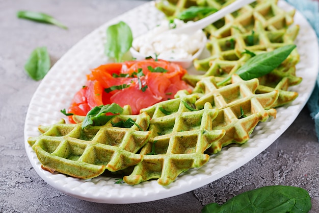 Savory waffles with spinach and cream cheese, salmon in white plate. Tasty food.