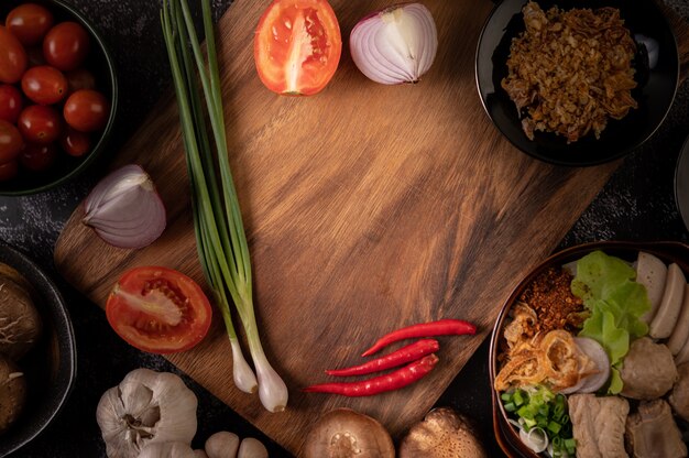 Scallions, peppers, garlic, and shiitake mushrooms on a wooden plate