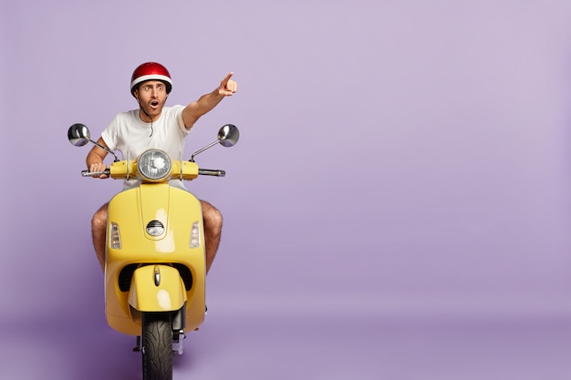 Free photo scared guy with helmet driving yellow scooter