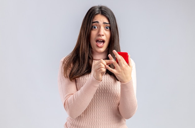 Scared looking at camera young girl on valentines day holding wedding ring isolated on white background