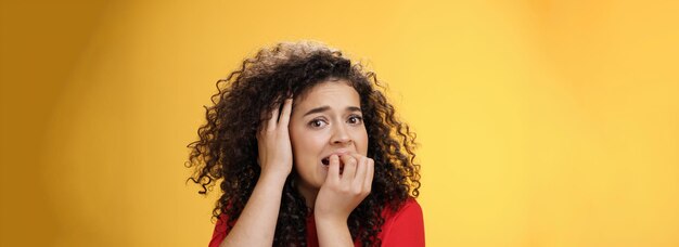 Scared woman overthinking frightened being in trouble biting fingers holding hand on head in despair