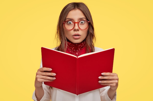 Free Photo scared young brunette with glasses posing against the yellow wall