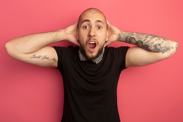 Free photo scared young handsome guy wearing headphones on neck grabbed head