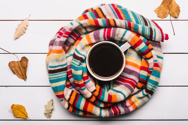 Scarf and autumn leaves lying around coffee