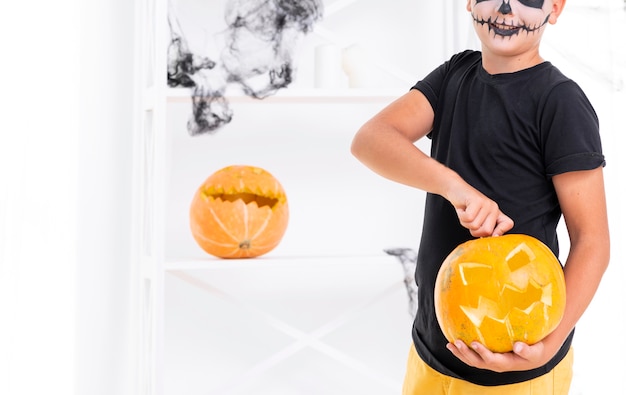 Scary boy holding carved pumpkin for halloween