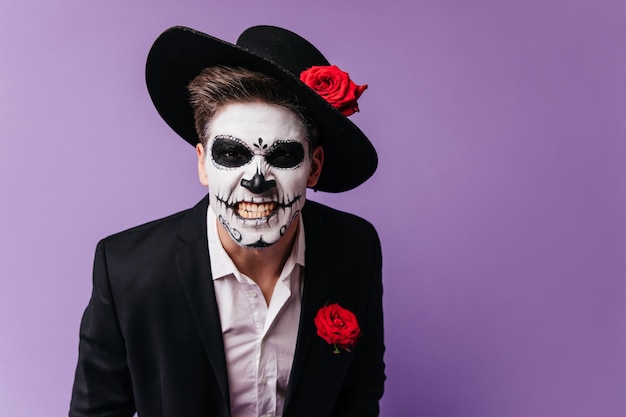 Scary guy in zombie outfit expressing rage. Studio photo of man in muertos costume fooling around during halloween party.