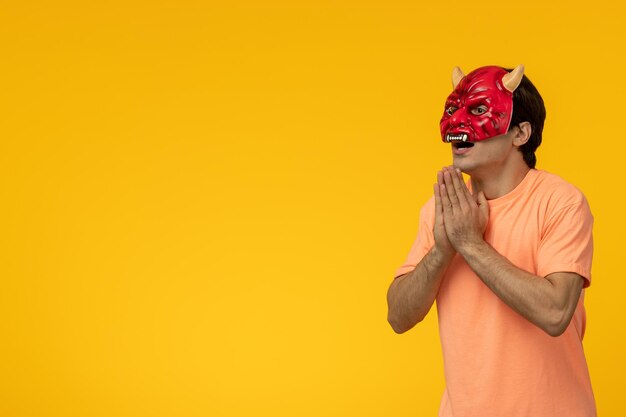 Scary mask young terrifying guy praying in evil red mask