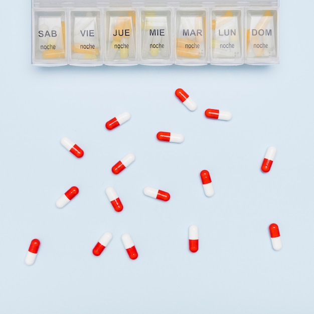 Free photo scattered capsules and pill organizer