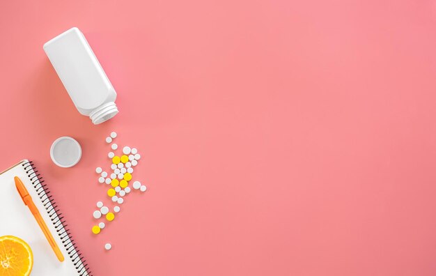 Scattered pills on a pink background flat lay