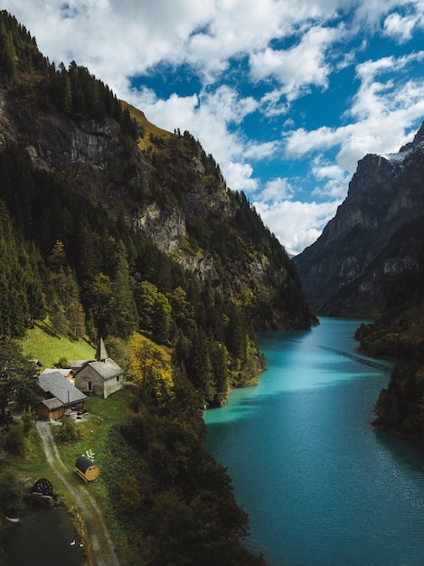 Free Photo scenery of a beautiful river between the mountains and small houses under the cloudy sky