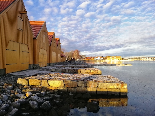 Scenery of buildings around the lake under the cloudy sky in Stavern Norway