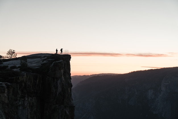 Scenery of people standing on top of a rock formation admiring the beauty of nature