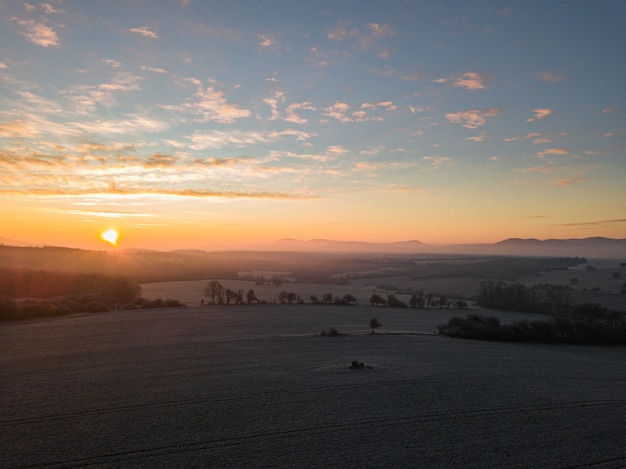 Scenery of sunset with an overlooking view of trees on the field and mountains