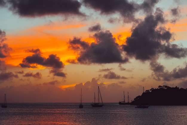 Scenery of sunset with a silhouette of mountain and boats in the sea