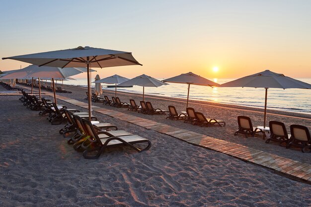 Scenic view of sandy beach on the beach with sun beds and umbrellas open against the sea and mountains. Hotel. Resort. Tekirova-Kemer. Turkey