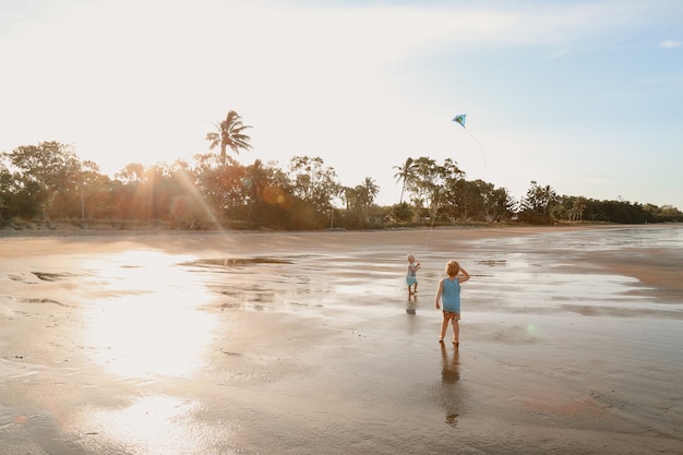 Scenic view of two white Caucasian kids with blond hair playing with a kite