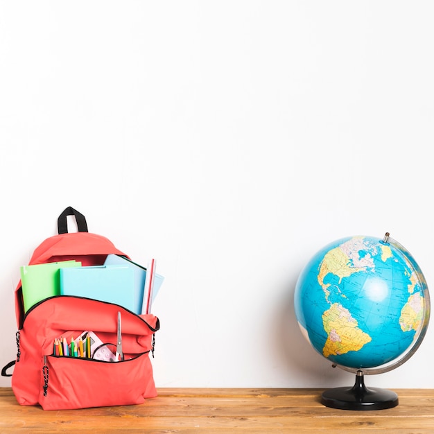 Free photo school bag with globe on table