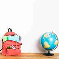 Free photo school bag with globe on table