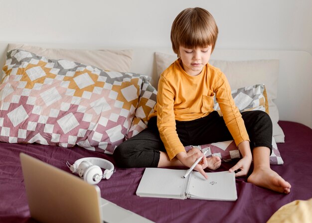 School boy sitting in bed long shot