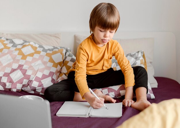 School boy sitting in bed virtual classes