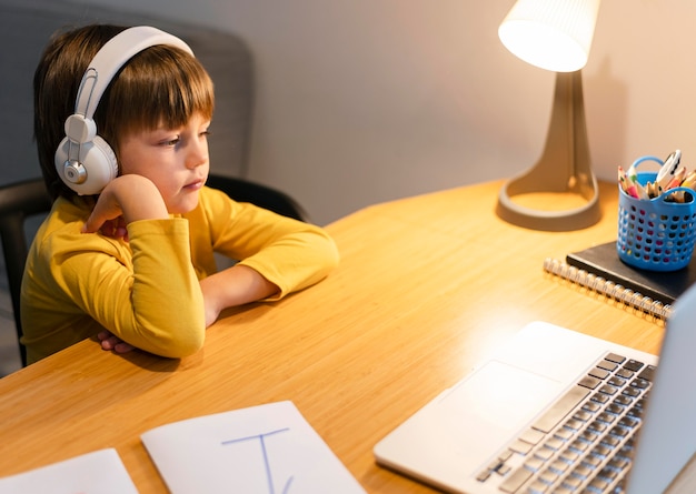 School boy in yellow shirt taking virtual classes high view