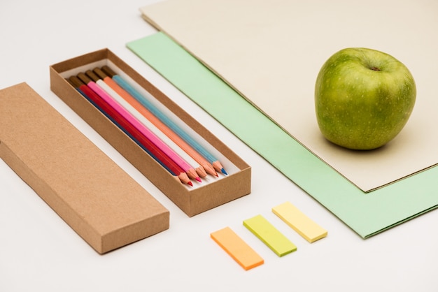 School supplies and apple on white table