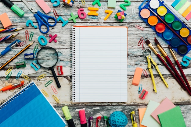 School supplies and notebook on wood background.