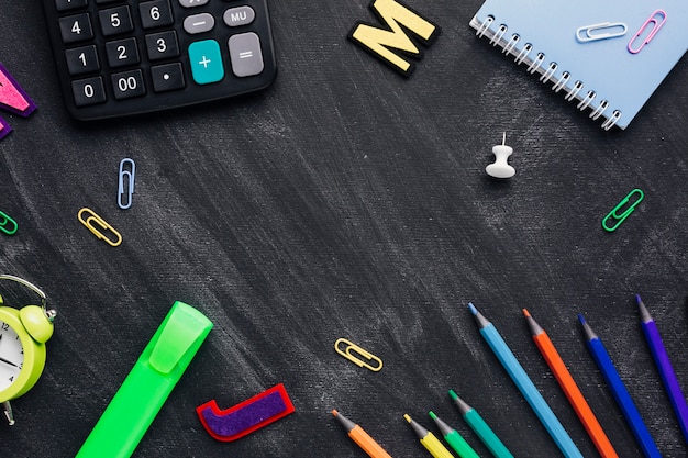 School supplies scattered like frame on chalkboard