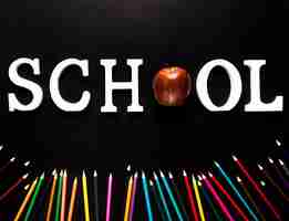 Free photo school word and strewn color pencils on black background