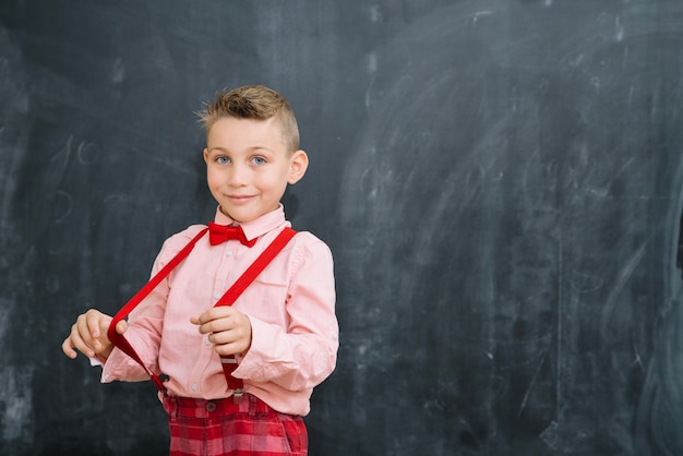 Free photo schoolboy pulling braces at blackboard