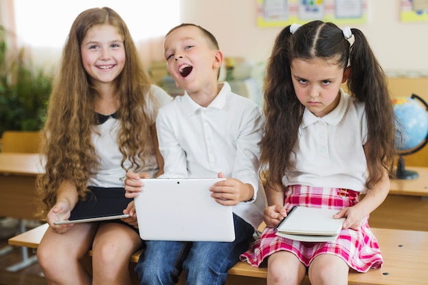 Free photo schoolchildren sitting on desk in classroom