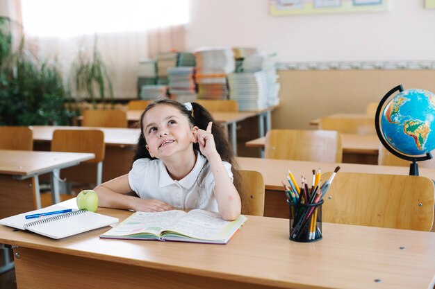 Schoolgirl pointing up in class