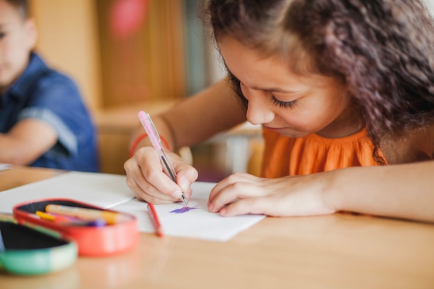 Schoolgirl sitting at table drawing