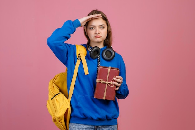 Schoolgirl standing holding hand on forehead searching