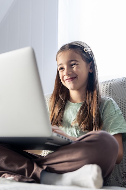 Free photo a schoolgirl studies online at home the girl is typing on the laptop keyboard