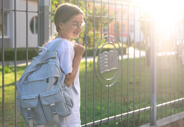 Free photo schoolgirl with a backpack on her shoulders school on the background of the sunset back to school