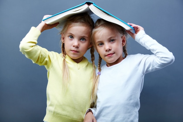 Free photo schoolgirls playing with an open book