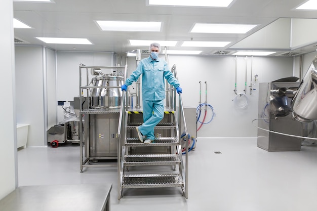 Free photo scientist in blue lab suit stand on metal chromed stairs with crossed legs