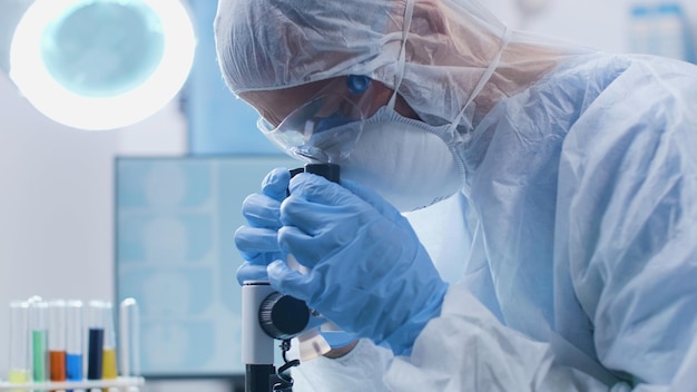 Scientist chemist looking into medical microscope analyzing dna sample during scientific experiment in biochemistry laboratory. Researcher doctor developing vaccine against covid19. Medicine concept