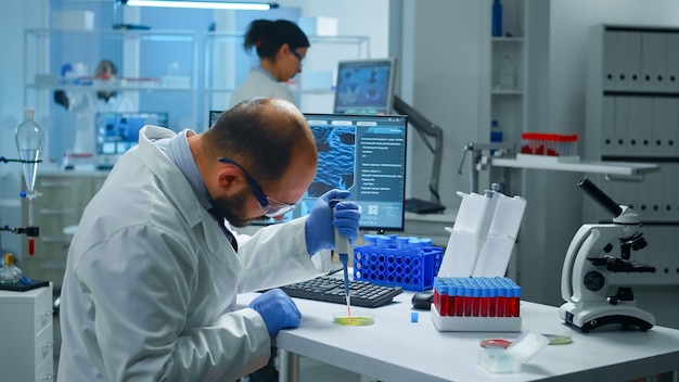 Free photo scientist putting blood sample from test tube with micropipette in petri dish analysing chemical reaction