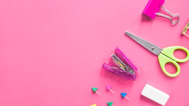 Free Photo scissors; stapler; bulldog clip; eraser and push pins on pink background