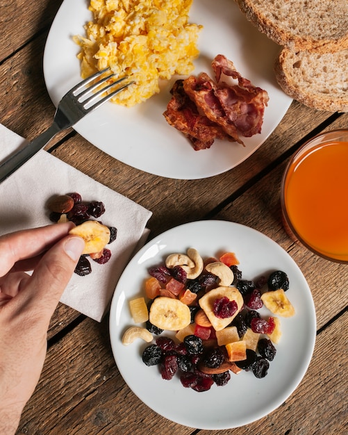 Free Photo scrambled eggs with bacon orange juice and dried fruits