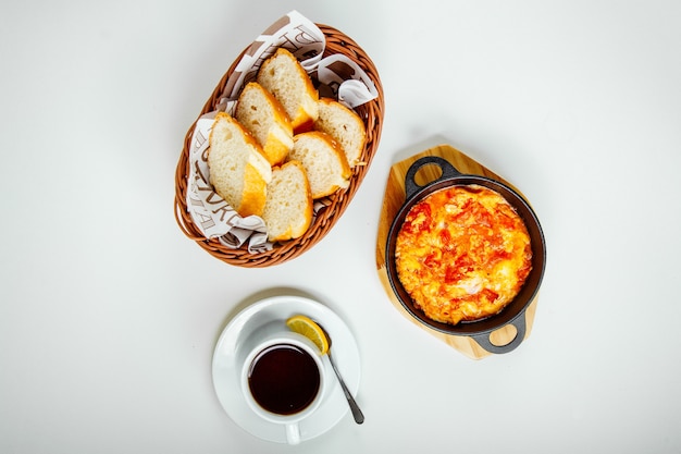 scrambled eggs with tomatoes, bread and a cup of tea