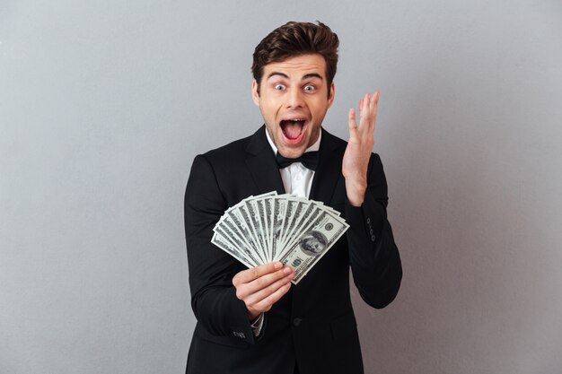 Screaming happy man in official suit holding money.