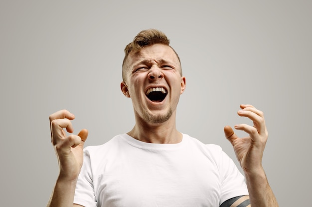 Free Photo screaming, hate, rage. crying emotional angry man screaming on gray studio background. emotional, young face. male half-length portrait. human emotions, facial expression concept.