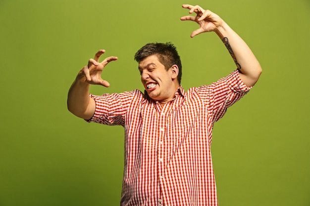 Free Photo screaming, hate, rage. crying emotional angry man screaming on green studio background. emotional, young face. male half-length portrait. human emotions, facial expression concept. trendy colors