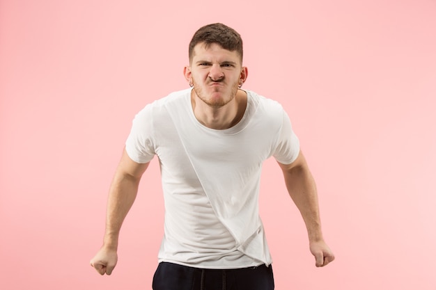 Screaming, hate, rage. Crying emotional angry man screaming on pink studio background. Emotional, young face. male half-length portrait. Human emotions, facial expression concept. Trendy colors