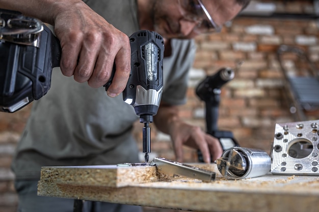 Free Photo screwing a self-tapping screw into a metal fastening hole on a wood strip using a screwdriver, the work of a carpenter.