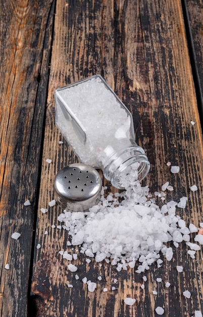 Sea salt coming out of open salt shaker with its cap