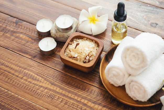 Sea salt, towels, aroma oil in bottles and flowers on vintage wooden background.